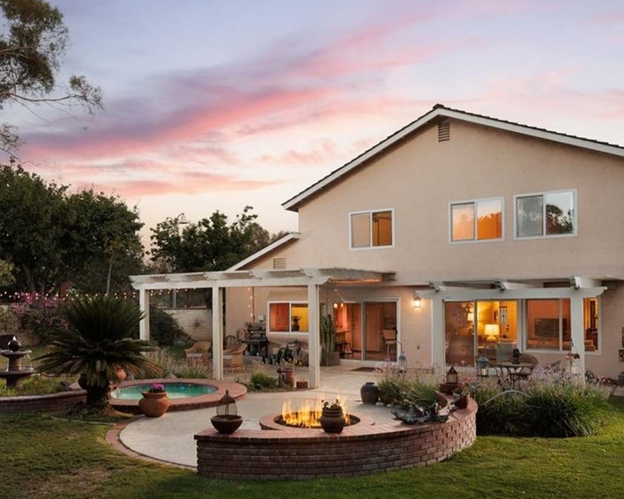 Two-story tract home backyard with fire pit, spa, and patio at sunset